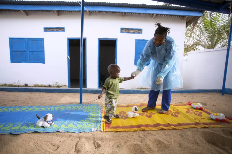 Tamba Manzare, 19 months old, and caregiver Rose Komano play outdoors at a UNICEF-supported nursery in Nzérékoré Region, Guinea. Tamba's mother died of Ebola.