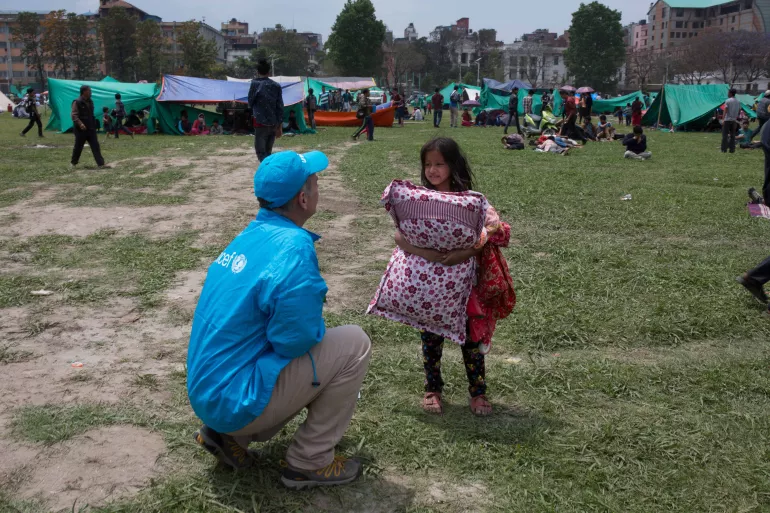 尼泊尔大地震后，联合国儿童基金会的工作人员在加德满都与一名正在寻找临时避难所的孩子交谈。