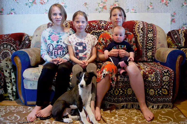 From left to right: Yana, 12, Lyubov, 10, Arina, 13 and Daniil, 7 months, sit in the living room of their small rented house in Nur-Sultan, Kazakhstan.