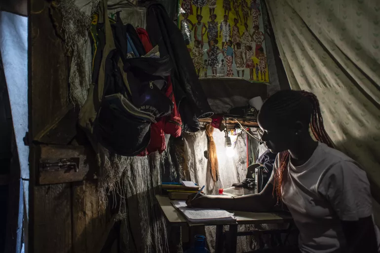 Sharlene, 14, studies at her mom's sewing table in the single-room home her family of 5 shares in Mathare.