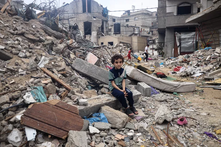 拉法市8岁的穆罕默德·阿拉塔尔（Mohammed Alattar）坐在他家房屋的废墟上，他家的房屋在以色列的空袭中被炸毁。