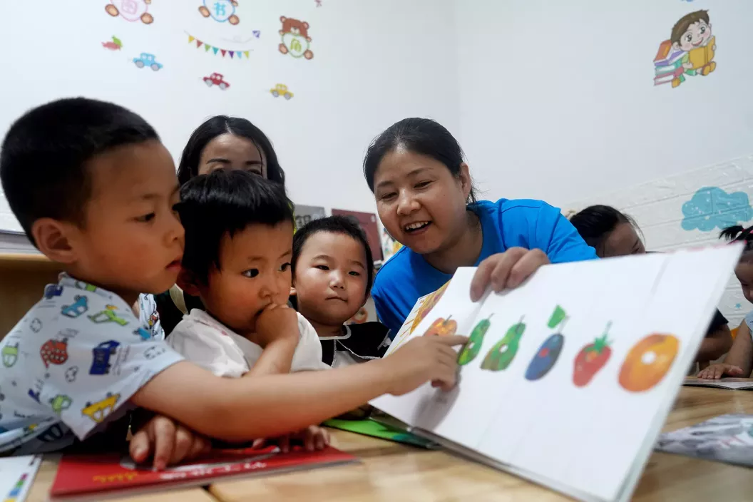A volunteer captivates young children with picture books at the early childhood development (ECD) centre of Chengxi Community in Zhang County on 2 August, 2023.